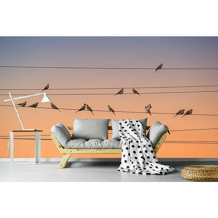 Papermoon Premium collection Fototapete Musik Des Lichts - B x H: 350 x 260 cm, Vlies - Ein stilvolles Wohnzimmer mit einem Holzbettsofa, weichen Kissen und einer schwarz-weißen gepunkteten Decke vor einer Wandtapete mit Vögeln.