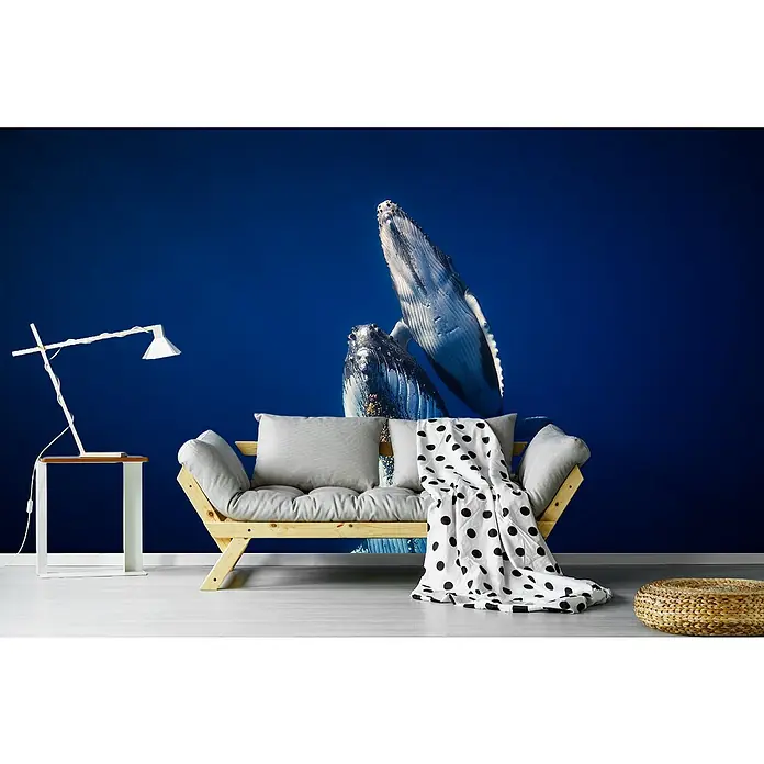 Papermoon Premium collection Fototapete Walfamilie zurück zur Oberfläche - B x H: 350 x 260 cm, Vlies - Einrichtung mit einer Fototapete mit zwei Walen, einem Holzbettsofa mit Kissen und einer Decke mit schwarzen Punkten, die eine ruhige Atmosphäre schafft.