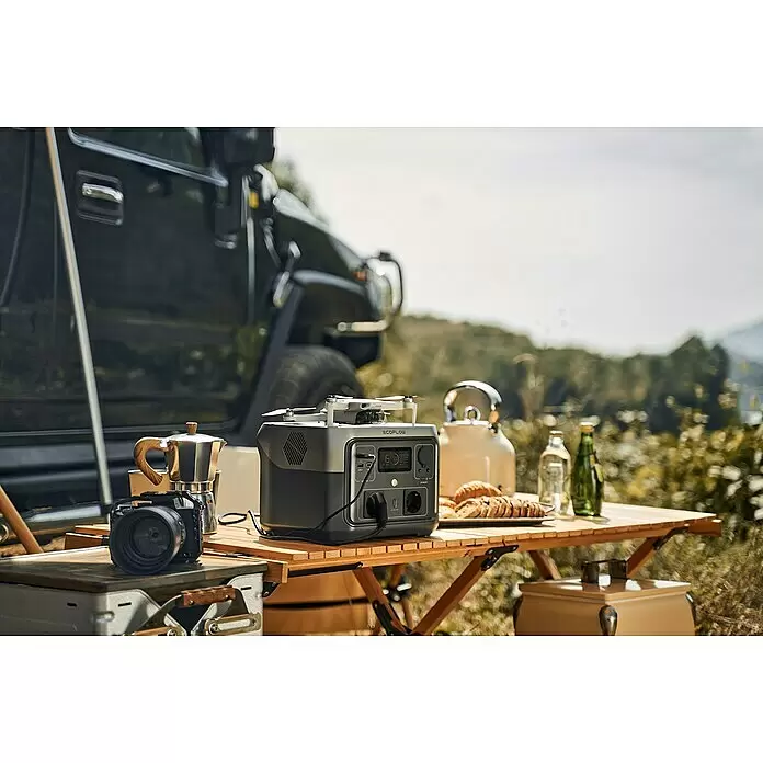 EcoFlow Estación de energía portátil River 2 Max - 512 Wh, Negro - Estación de energía portátil EcoFlow gris cargando un dron y alimentando café en una mesa de madera al aire libre junto a un vehículo.