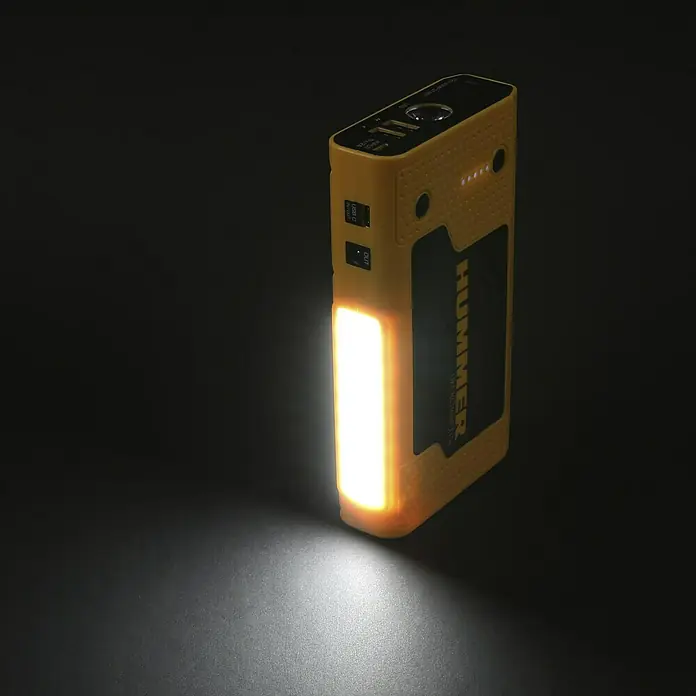 Kit de arranque HUMMH3T - 12 V, 3 Ah - 8 Ah - Un arrancador de batería Hummer amarillo con luz incorporada que ilumina una habitación oscura, ofreciendo un arranque fiable.
