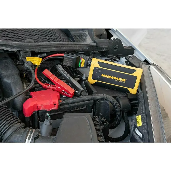 Kit de arranque HUMMHX - 12 V, 3 Ah - Un arrancador de batería Hummer amarillo está conectado a una batería de coche con cables de puente.