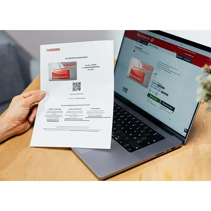 Gutscheinkarte - Zum Selbstausdruck, 20 Euro, Werkzeugkasten - Bauhaus Gutscheinkarte im Wert von 60,00 € neben einem Laptop mit der Bauhaus Webseite. Ideal für Heimwerker und Bauprojekt-Enthusiasten.