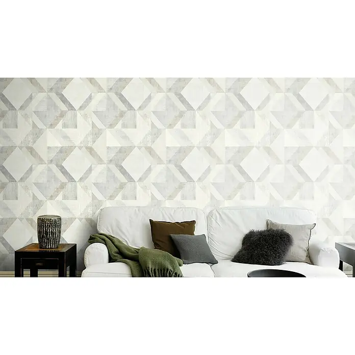Rasch Color your life Vliestapete - Grau, Beige, Braun, Grafisch, 10,1 x 0,53 m - Nahaufnahme einer gemusterten Wand mit einem weißen Sofa, Kissen und Beistelltisch, die ein stilvolles und modernes Interieur präsentieren.