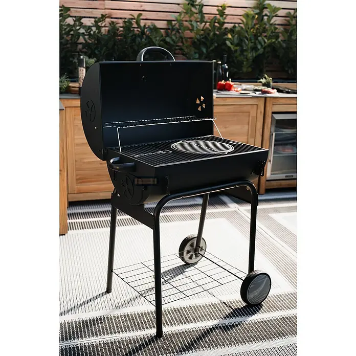 Grillstar Holzkohlegrill GrilltonneB x T x H: 109 x 71 x 87 cm, Grillfläche (B x T): 64 x 43 cm, Schwarz - Schwarzer Kugelgrill mit offenem Deckel auf einer Terrasse. Der Grill verfügt über ein Fahrgestell mit Ablage und Rädern für einfachen Transport.
