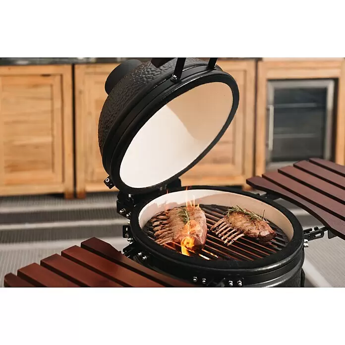 Kingstone Holzkohlegrill Kamado 38 - Durchmesser Grillfläche: 38,3 cm, Schwarz - Offener schwarzer Kamado-Grill mit weißer Keramikinnenseite, der zwei Lammracks mit Flammen in einer Außenküche grillt.