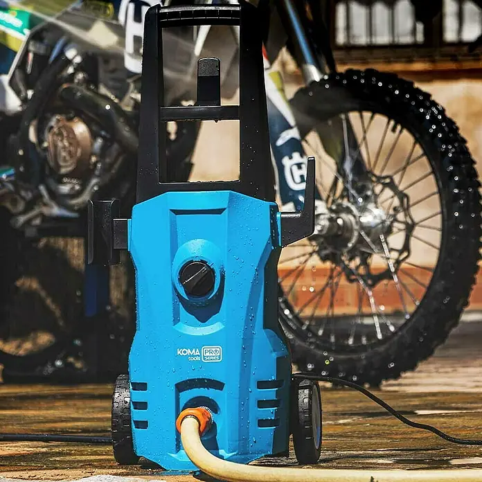 Koma Tools PRO Series Hidrolimpiadora de alta presión - 120 bar, 1.400 W, Capacidad de bombeo: 432 l/h - La hidrolavadora Koma Pro Tools Series, una potente solución para las tareas de limpieza exterior, se encuentra frente a una moto.