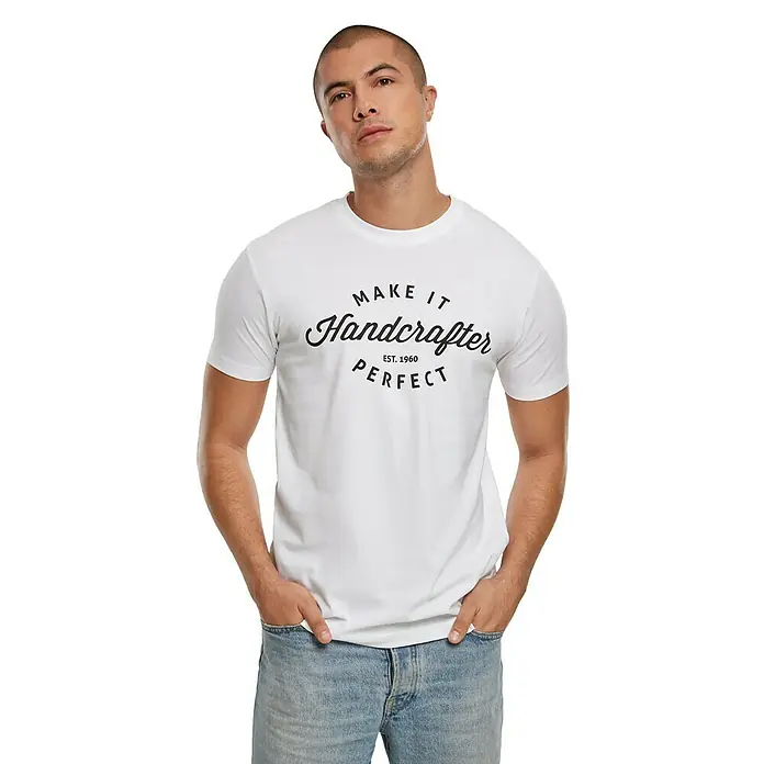 T-Shirt Handcrafter - Weiß, XXXL - Ein Mann präsentiert ein weißes T-Shirt mit dem Aufdruck "Make It Handcrafter Perfect Est. 1960", kombiniert mit Jeans für einen lässigen Look.