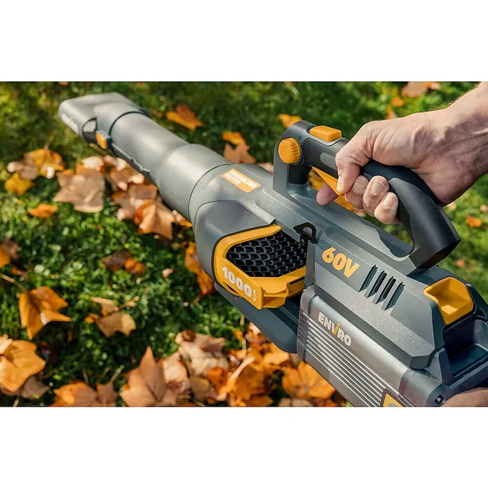 Worx ENVIRO Akku-Laubbläser EG560.9 - 60 V, Ohne Akku, Blasgeschwindigkeit: 200 km/h, Blasleistung: 1.000 m³/h - Nahaufnahme eines Enviro 60V Akku-Laubbläsers über herabgefallenen Blättern im Gras, der mit einer Hand bedient wird.