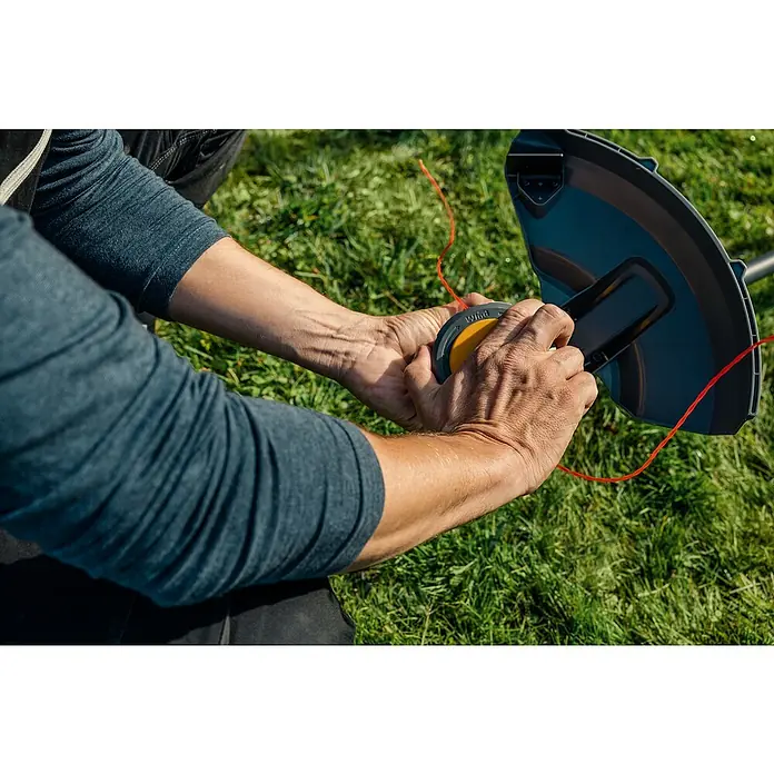 Worx ENVIRO Akku-Rasentrimmer EG161.9 - 60 V, Ohne Akku - Nahaufnahme einer Person, die den Fadenkopf eines Rasentrimmers auf einem Rasen neu bespult.