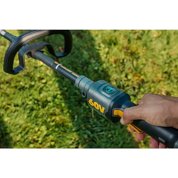 Worx ENVIRO Akku-Rasentrimmer EG161.9 - 60 V, Ohne Akku - Nahaufnahme eines 60V Akku-Rasentrimmers mit Bedienelementen und einem Bediener, der den Trimmer hält, im Hintergrund Rasen.