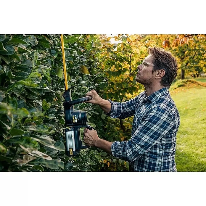 Worx ENVIRO Akku-Heckenschere EG261.9 - 60 V, 2 Ah, 1 Akku - Mann mit Schutzbrille schneidet eine grüne Hecke mit einem schwarzen und gelben Akku-Heckenschneider mit silbernem Akku.