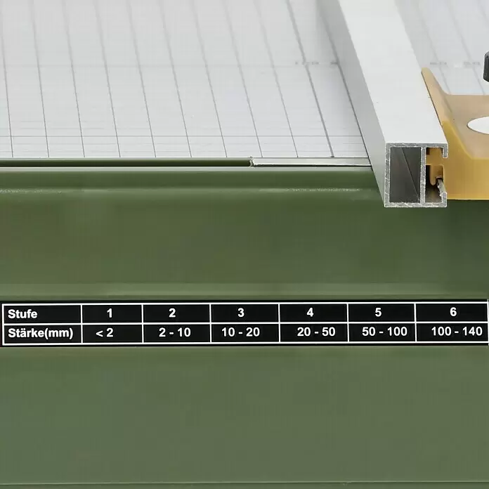 Proxxon Micromot Heißdraht-Schneidegerät Thermocut 230/E - 1 x Heißdraht-Schneidegerät Thermocut 230/E, 1 x Sattel und Drahtspule (30 m Schneidedraht Ø 0,2 mm) - Nahaufnahme einer olivgrünen Schneidemaschine mit weißer Gitterarbeitsfläche und silberner Führung, zeigt eine deutsche Dicken-Einstellungstabelle von <2mm bis 140mm.
