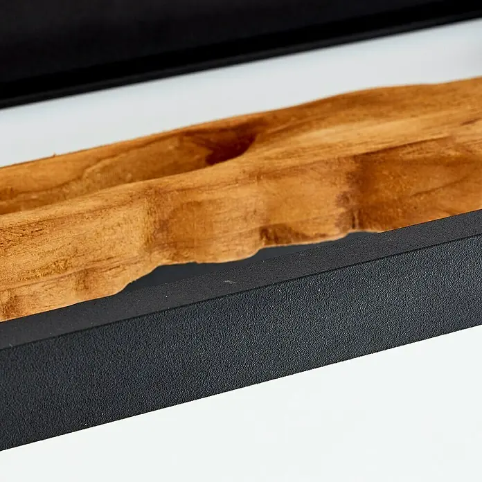 Brilliant LED-Wandleuchte Chaumont - 9,5 W, L x B x H: 10 x 35 x 15,1 cm, Schwarz, Warmweiß - Detailaufnahme eines Teakholz-Accessoires mit Rahmen. Das Holzstück liegt in einem schwarzen Behälter mit einem weißen Hintergrund.