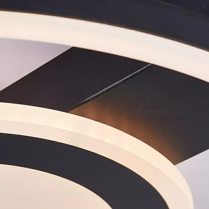 Brilliant LED-Deckenleuchte Maureen - 22 W, L x B x H: 37 x 37 x 5 cm, Schwarz, Warmweiß - Nahaufnahme einer modernen LED-Deckenleuchte mit schwarzen Metallelementen und geschwungenen, leuchtenden weißen Lichtstreifen.