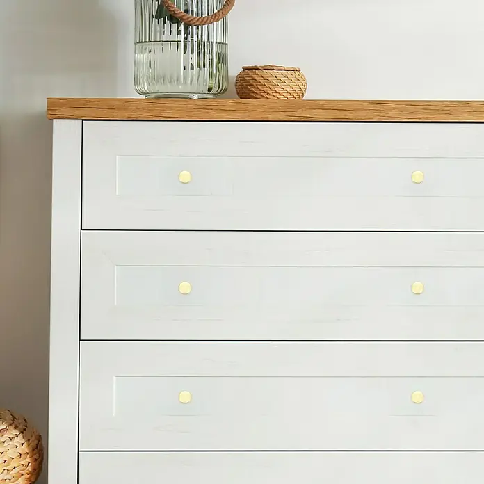 Häfele Pomo para muebles - Tipo de tirador del mueble: Botón, Ø x Al: 25 x 22 mm, Dorado - Una cómoda blanca con una mesa de madera, adornada con pomos dorados, con un jarrón de vidrio y una cesta.