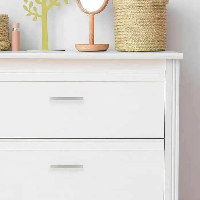 Rei Tirador para muebles - Largo: 120 mm, Tipo de tirador del mueble: Barra, Aluminio - Primer plano de una cómoda blanca con dos cajones y tiradores plateados, decorada con elementos naturales.