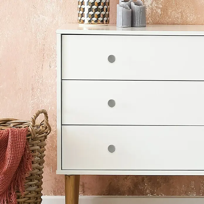 Häfele Pomo para muebles - Tipo de tirador del mueble: Botón, Características del diseño: Acero inoxidable, Ø x L: 25 x 22 mm, Mate - Primer plano de una cómoda blanca con tres cajones y pomos plateados, que desprende un diseño moderno y minimalista.
