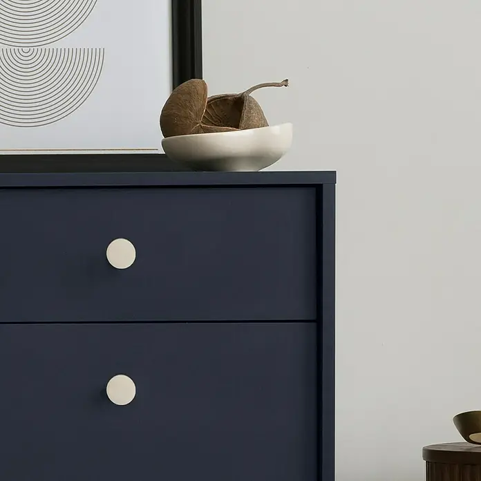 Häfele Pomo para muebles - Tipo de tirador del mueble: Botón, Ø x Al: 14 x 26 mm, Niquelado, Mate - Primer plano de una cómoda azul con dos cajones con pomos redondos y blancos, adornada con un cuenco blanco y obra de arte.