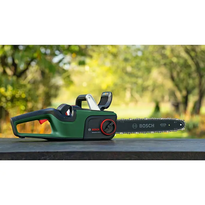 Bosch Power for All 36V Akku-Kettensäge AdvancedChain 36V-35-40 - 36 V, Li-Ionen, Ohne Akku, Schwertlänge: 35 cm - Nahaufnahme einer grünen Bosch AdvancedChain 36V-35 Akku-Kettensäge auf einem Tisch, im Hintergrund Bäume.