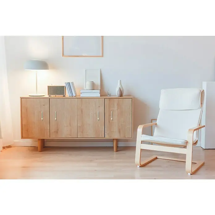 MöbelgriffTyp Möbelgriff: Stange, Lochabstand: 64 mm - Ein stilvolles Sideboard aus Holz mit hellen Akzenten, ergänzt durch eine sanfte Beleuchtung und einen modernen Sessel.