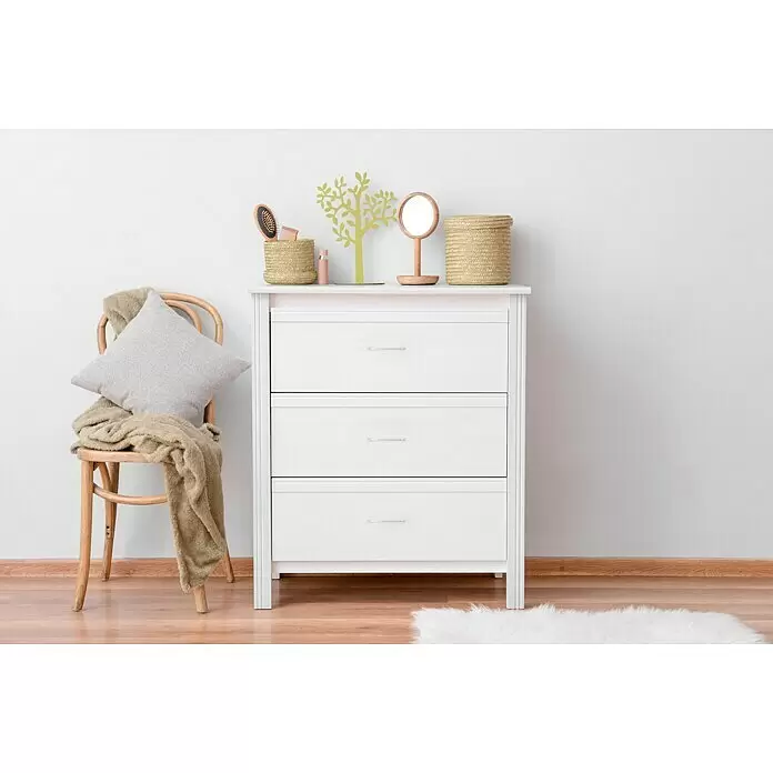 Häfele Möbelgriff - Typ Möbelgriff: Bügel, L x B x H: 144 x 28 x 8 mm, Sonstige, Verchromt, Silber - Weißes Kommode mit drei Schubladen, klaren Griffen, darauf geflochtene Körbe und ein Deko-Baum, daneben ein Stuhl mit Kissen und Decke.
