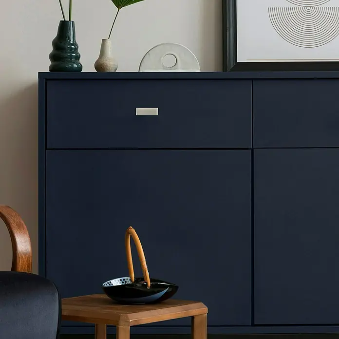 Möbelgriff - Vernickelt, B x L: 24 x 48 mm - Elegantes, marineblaues Sideboard mit minimalistischem Design und silberfarbenen Griffen, dekoriert mit Vasen und einem modernen Kunstwerk.