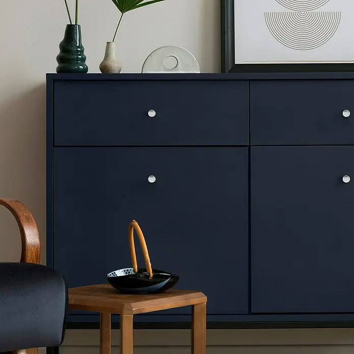 Häfele Pomo para muebles - Tipo de tirador del mueble: Botón, Cromado - Elegante toma de un aparador azul marino con pomos plateados, decorado con jarrones y una obra de arte moderna.
