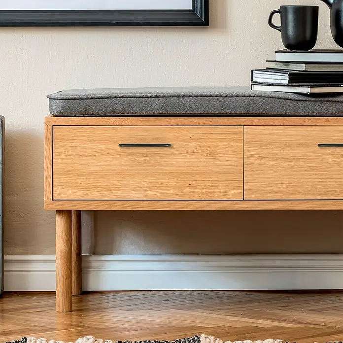 Häfele Tirador para muebles - Tipo de tirador del mueble: Estribo, Acero, Lacado - Primer plano de un banco de madera con cojín gris, cajones con tiradores negros elegantes y libros y tazas decorativas. Diseño funcional.
