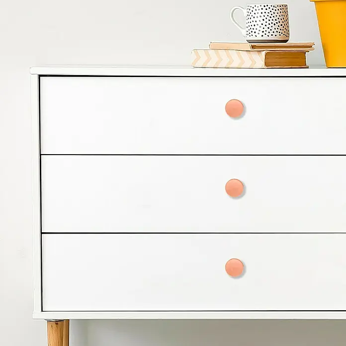 Möbelknopf-Set - 2 Stk., Typ Möbelgriff: Knopf, Ø x H: 60 x 19 mm, Roségold - Eine Nahaufnahme einer weißen Kommode mit drei Schubladen und runden, pfirsichfarbenen Knöpfen.
