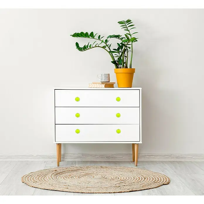 Häfele Pomo para muebles - Tipo de tirador del mueble: Botón, Plástico, Cromado, Verde - Cómoda blanca con seis pomos verde claro como pelotas de tenis sobre una alfombra beige, con una planta encima.