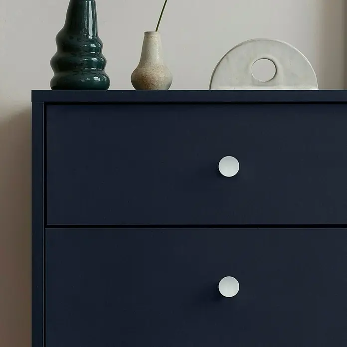 Häfele MöbelknopfTyp Möbelgriff: Knopf, Durchmesser: 12 mm - Nahaufnahme einer marineblauen Kommode mit zwei Schubladen und runden, weißen Knöpfen, dekoriert mit Vasen und einem modernen Dekorationsstück.