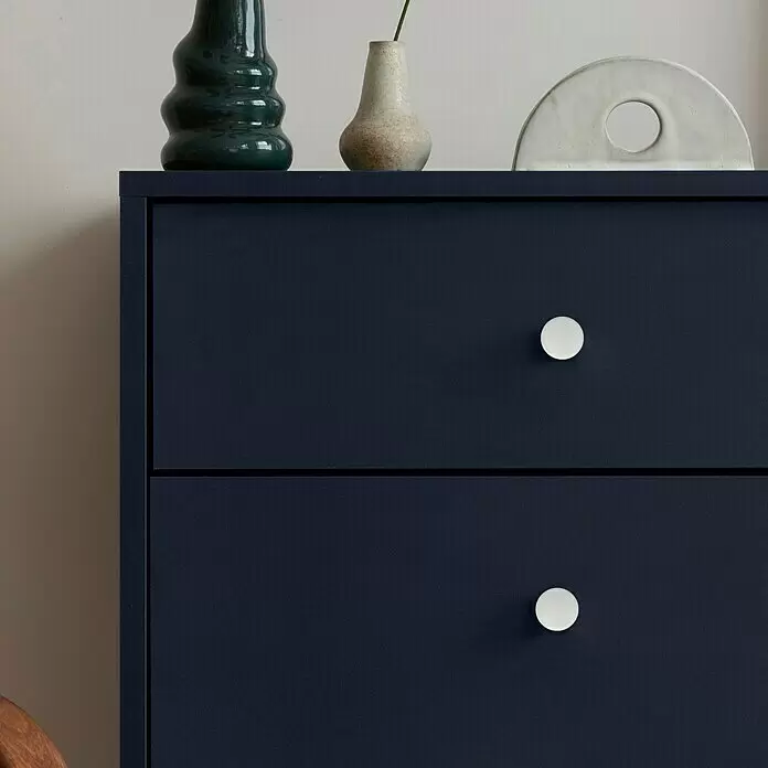 Häfele Pomo para muebles - Tipo de tirador del mueble: Botón, Ø x Al: 25 x 18 mm - Cómoda azul oscuro con dos tiradores redondos blancos, decorada con jarrones y una escultura encima.