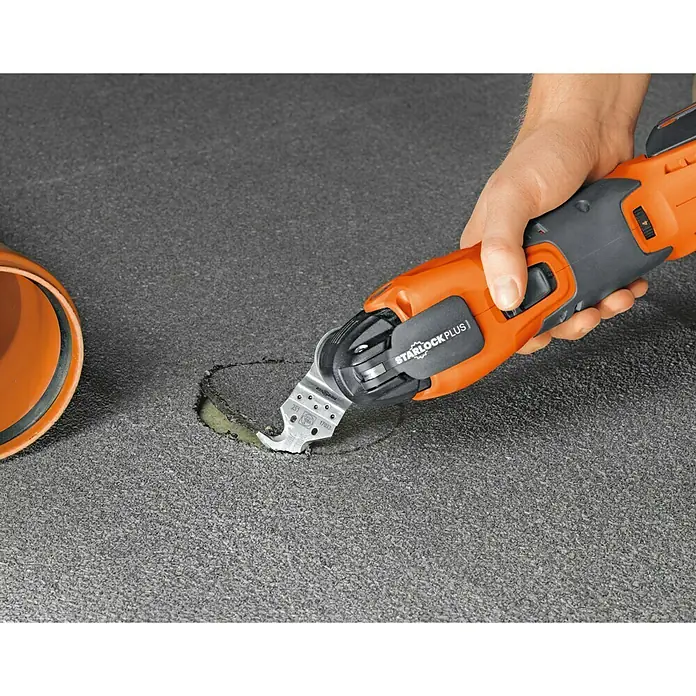 Fein Starlock Multi-Messer - Geeignet für: Teppichboden, 1 Stk. - Eine StarlockPlus Multifunktionswerkzeug schneidet präzise ein Loch in eine graue Oberfläche, eine orangefarbene Röhre liegt daneben.