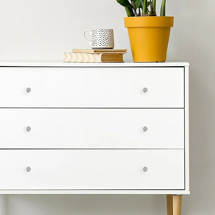 Häfele Pomo para muebles - Tipo de tirador del mueble: Botón, Ø x Al: 14 x 26 mm, Cromado, Mate - Cómoda blanca con tres cajones y tiradores redondos, decorada con plantas, taza y libros.