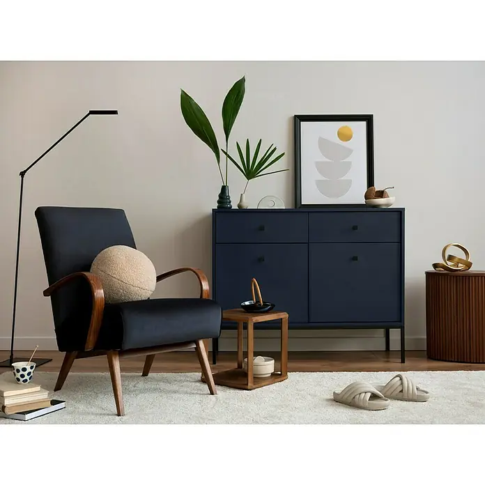 Häfele Möbelknopf - Typ Möbelgriff: Knopf, Eisen - Elegantes Interieur mit dunkelblauem Sideboard, Sessel mit rundem Kissen, Stehlampe und Deko-Elementen für ein stilvolles Wohnambiente.