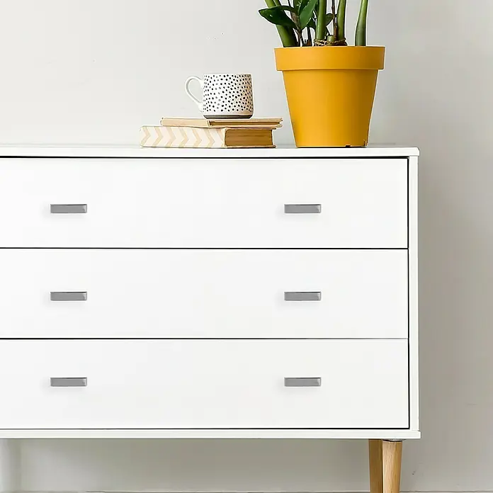 Häfele Tirador para muebles - Tipo de tirador del mueble: Barra, L x An x Al: 40 x 24 x 10 mm, Cromado - Cómoda blanca con tres cajones y una parte superior decorada con objetos. Diseño elegante y moderno para tu hogar.