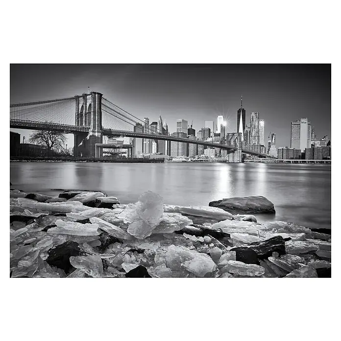 Papermoon Premium collection Fototapete New York Brooklybridge - B x H: 450 x 280 cm, Vlies - New Yorker Skyline und Brooklyn Bridge in Schwarzweiß. Im Vordergrund liegen Eisstücke am Ufer, die die kalte Jahreszeit widerspiegeln.