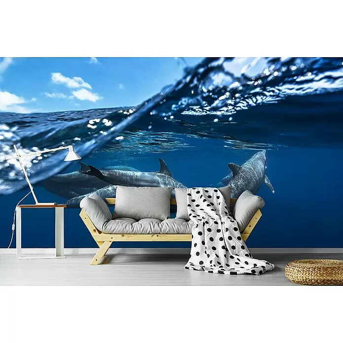 Papermoon Premium collection Fototapete Delphine II - B x H: 250 x 186 cm, Vlies - Ein Sofa aus Naturholz mit grauen Kissen und einer weißen Decke mit schwarzen Punkten steht in einem Raum.