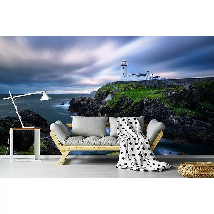Papermoon Premium collection Fototapete Fanad Head Leuchtturm - B x H: 350 x 260 cm, Vlies - Ein helles Holzfuton mit grauen Kissen, gepunkteter Decke, Beistelltisch, Lampe und geflochtenem Hocker in einem Raum.