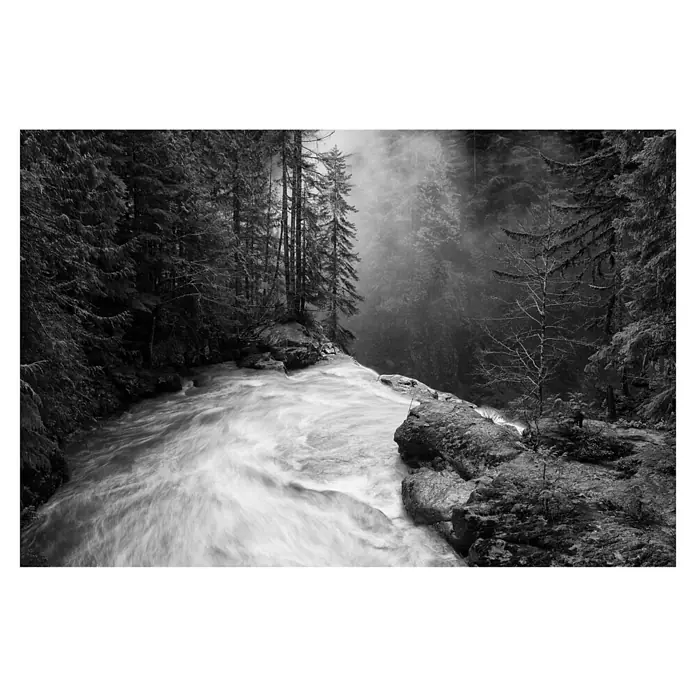 Papermoon Premium collection Fototapete Über den Fällen - B x H: 200 x 149 cm, Vlies - Schwarzweißaufnahme eines Wasserfalls im Wald. Das Wasser fließt schnell über die Felsen, umgeben von Bäumen und Nebel.
