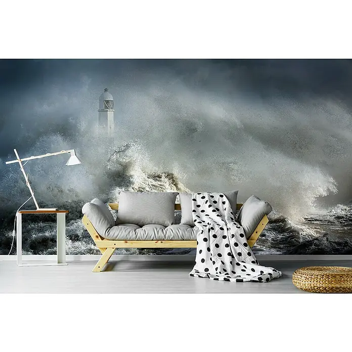Papermoon Premium collection Fototapete Mayhem am Leuchtturm - B x H: 450 x 280 cm, Vlies - Wohnzimmer mit einem hellen Holzbettsofa, grauem Kissen und einer schwarz-weiss gepunkteten Decke im Vordergrund einer stürmischen Ozean Tapete.