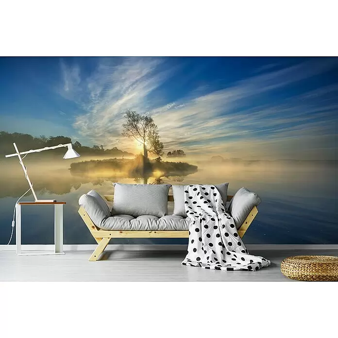 Papermoon Premium collection Fototapete Die Insel - B x H: 350 x 260 cm, Vlies - Ein helles Holzsofa mit grauen Kissen und einer weiß gepunkteten Decke steht in einem Raum mit einem See-Wandbild, neben einem Beistelltisch und einer Lampe.