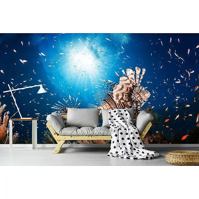 Papermoon Premium collection Fototapete Lionfish - B x H: 250 x 186 cm, Vlies - Wandtapete mit Unterwasser-Lionfish- und Fischmotiv hinter einem hellen Holzsofa mit grauen Kissen, einer gepunkteten Decke und einem Beistelltisch.