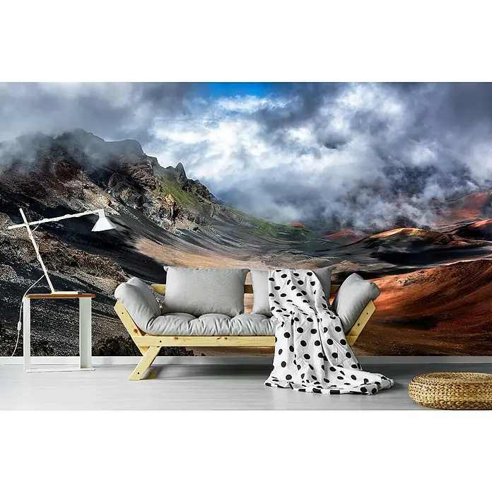 Papermoon Premium collection Fototapete Kraterkante - B x H: 250 x 186 cm, Vlies - Wohnzimmer mit Bergkulisse: Gemütliches Sofa mit Kissen und Decke vor einer beeindruckenden Berglandschaft mit Nebel und Wolken.