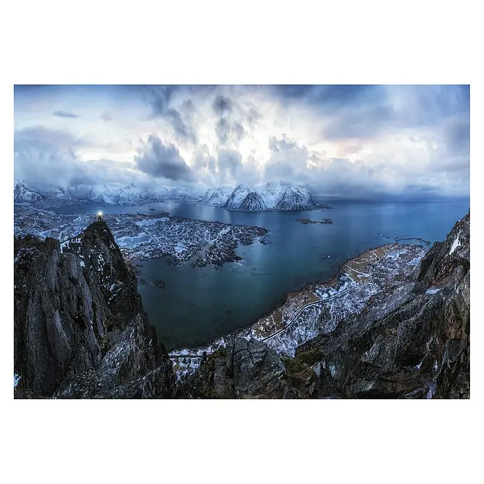 Papermoon Premium collection Fototapete Im Himmel auf Hazven - B x H: 200 x 149 cm, Vlies - Landschaftsfoto mit verschneiten Bergen, Gewässern und dramatischer Wolkendecke. Ein Lichtpunkt markiert eine Person auf einem Berggipfel.