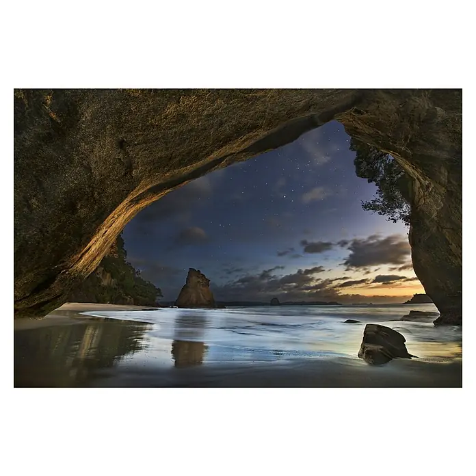 Papermoon Premium collection Fototapete Cathedral Cove - B x H: 250 x 186 cm, Vlies - Blick durch eine Felsenhöhle auf einen Strand bei Nacht, Sterne funkeln am Himmel und das Wasser spiegelt das Licht wider.