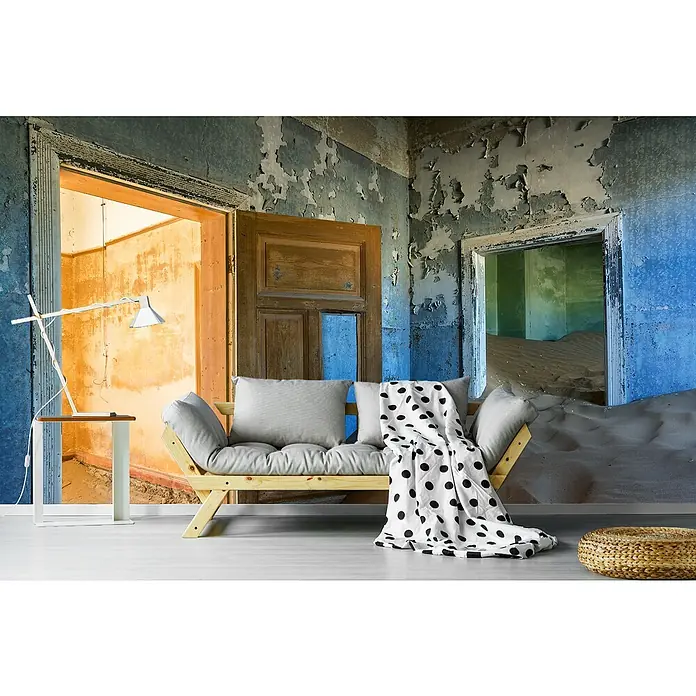 Papermoon Premium collection Fototapete Verschwinden in der Vergessenheit - B x H: 250 x 186 cm, Vlies - Das Bild zeigt ein modernes Futon-Sofa mit einem weißen Bezug mit schwarzen Punkten, das vor einer verfallenen Wand steht.