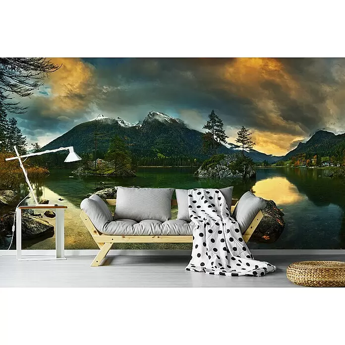 Papermoon Premium collection Fototapete Hintersee - B x H: 250 x 186 cm, Vlies - Holzbett mit grauen Kissen und gepunkteter Decke, weißer Beistelltisch mit Lampe und geflochtener Pouf vor Naturwandbild.