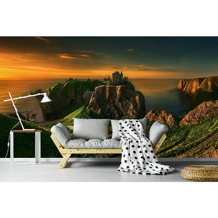 Papermoon Premium collection Fototapete Dunnottar - B x H: 250 x 186 cm, Vlies - Gemütliches Interieur mit einem Holzbettsofa, Kissen, Decke und einem atemberaubenden Landschaftsbild an der Wand.