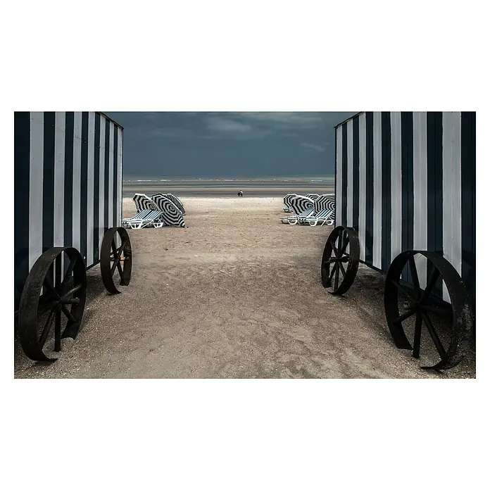 Papermoon Premium collection Fototapete La Visante - B x H: 350 x 260 cm, Vlies - Streifenkabinenwagen mit grossen Rädern am Strand unter einem dunklen Himmel. Die Kabinenwagen sind blau-weiss gestreift und mit Rädern versehen.